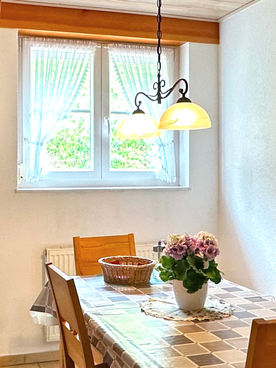 Esszimmer der Ferienwohnung Zwei Linden – Esstisch mit Blumenvase, Fenster mit Gartenblick